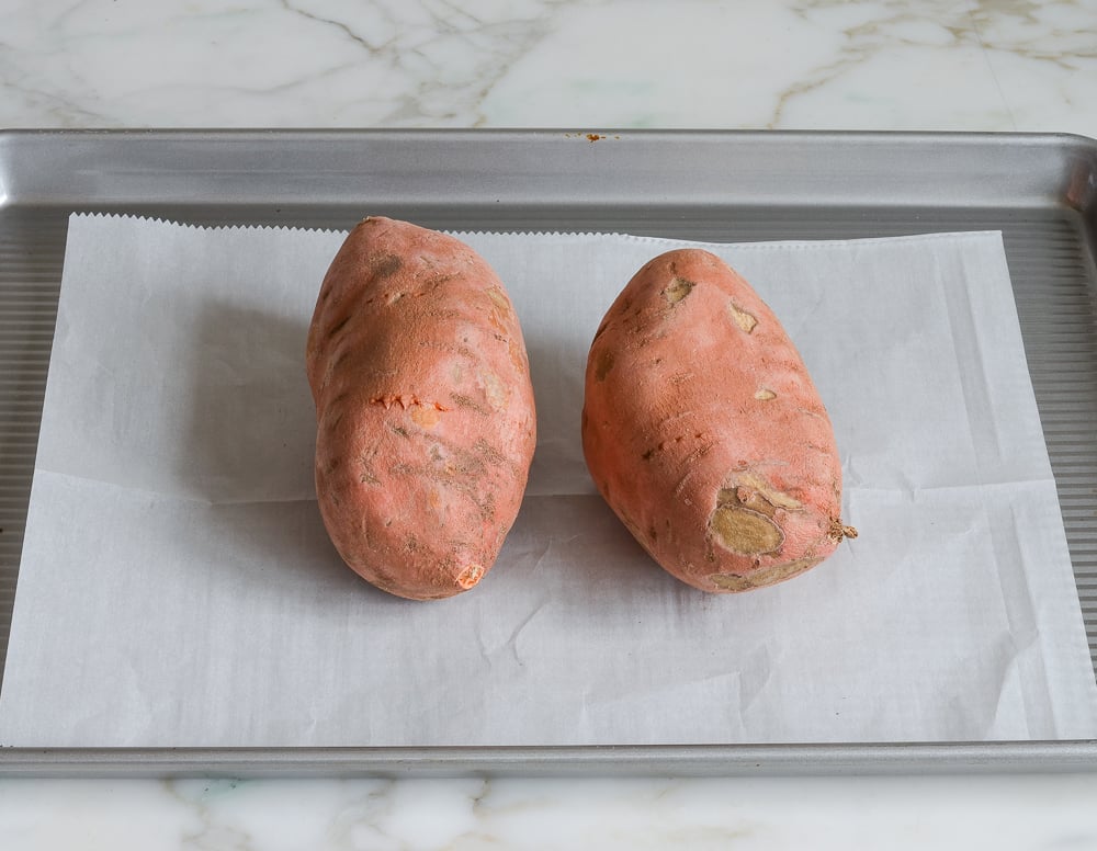 poked sweet potatoes on baking sheet