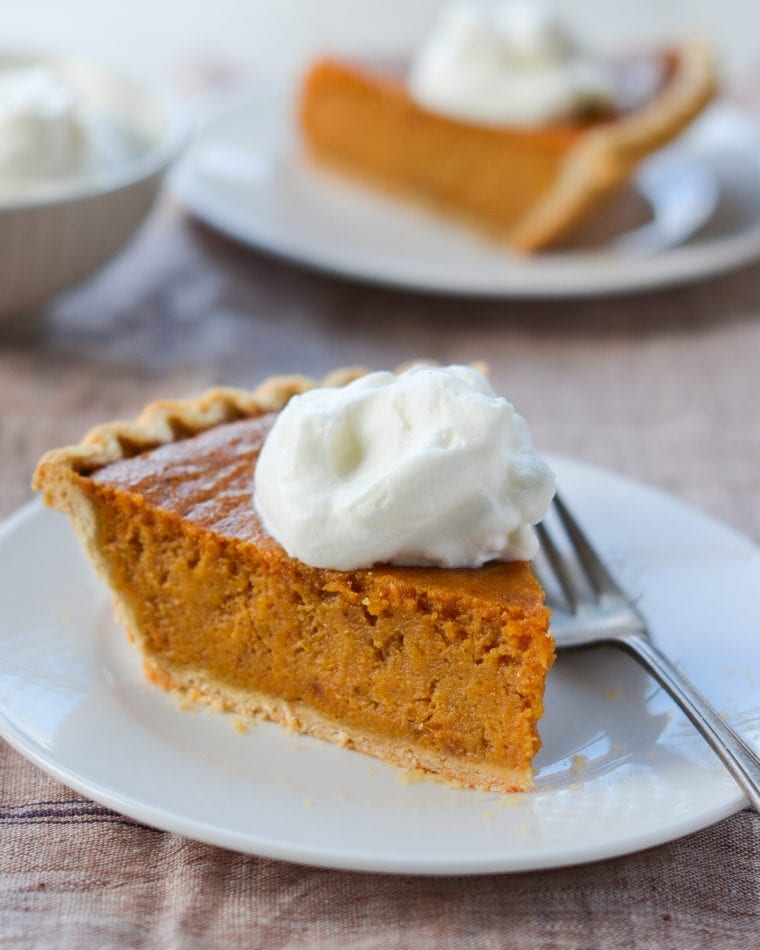Slice of sweet potato pie on a plate with a fork.