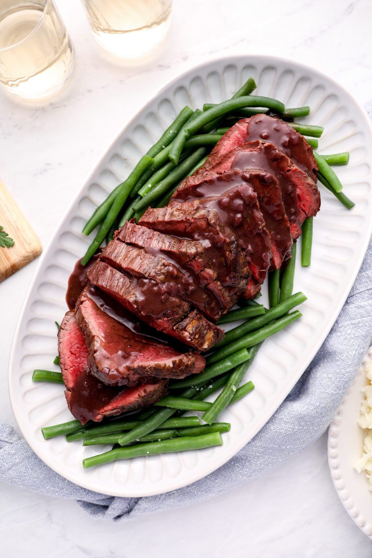 Roast beef tenderloin on a platter with green beans.