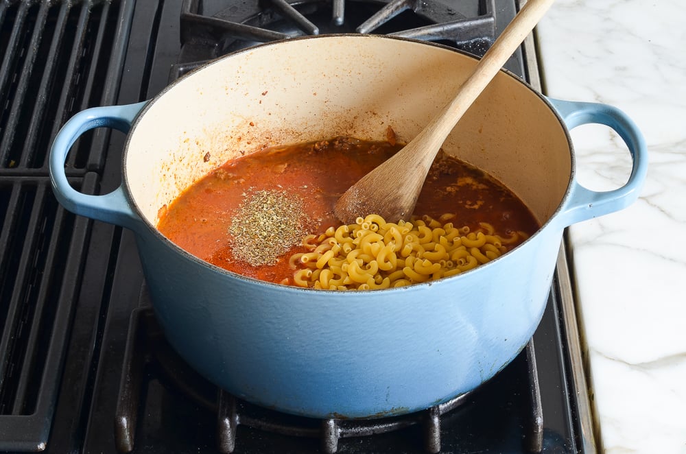 adding broth, tomato sauce, pasta to beef mixture
