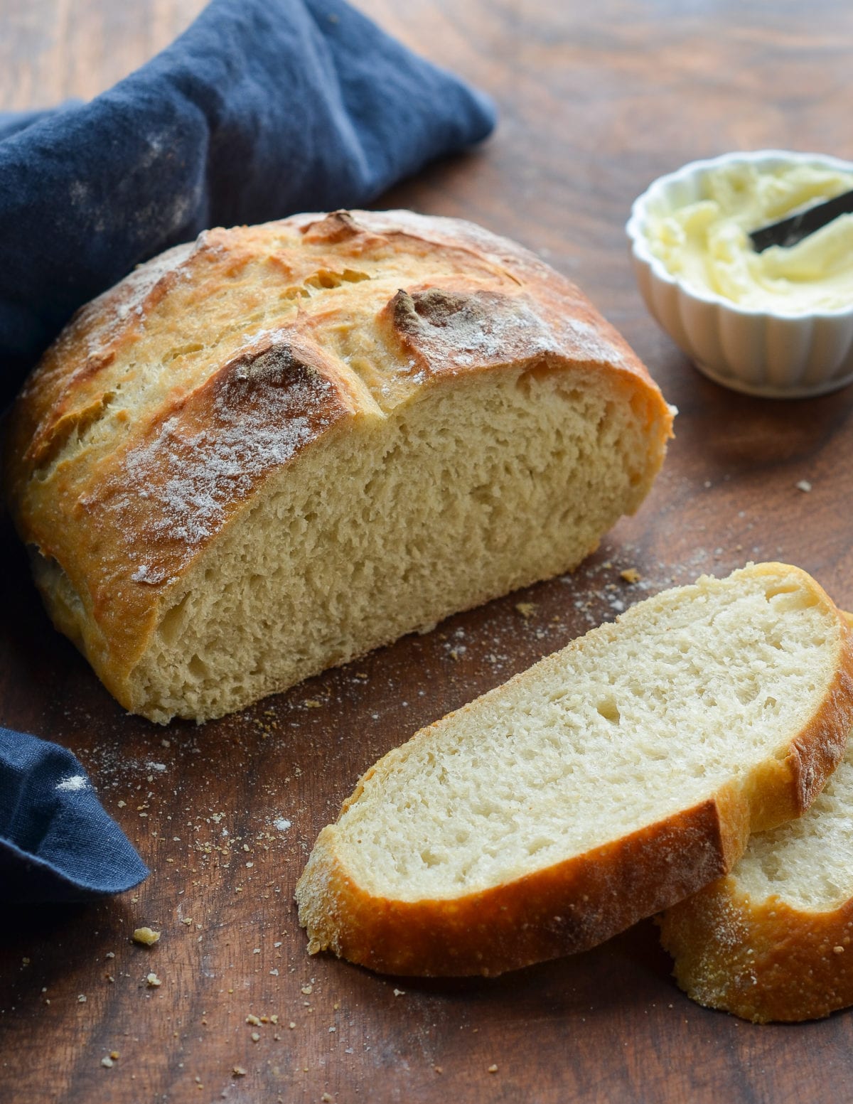 Partially-sliced loaf of crusty artisan bread.