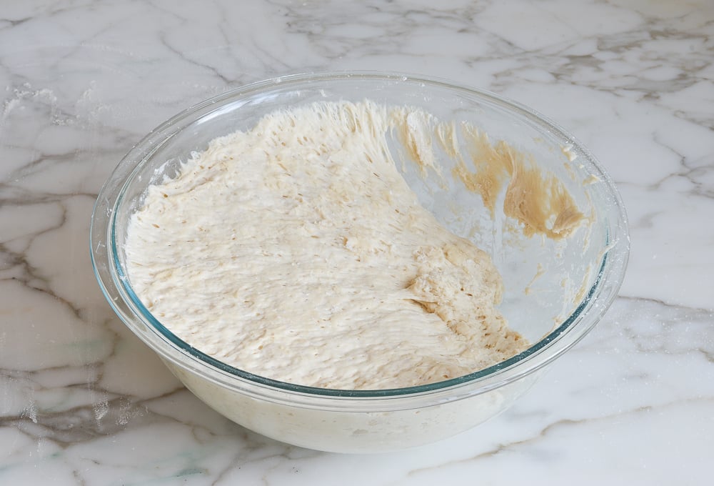 removing some of the bread dough from the bowl