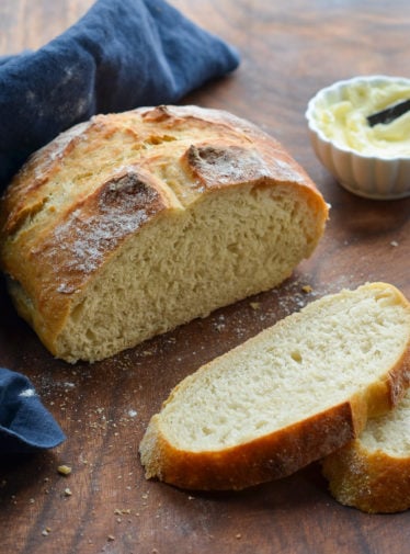 Partially-sliced loaf of crusty artisan bread.