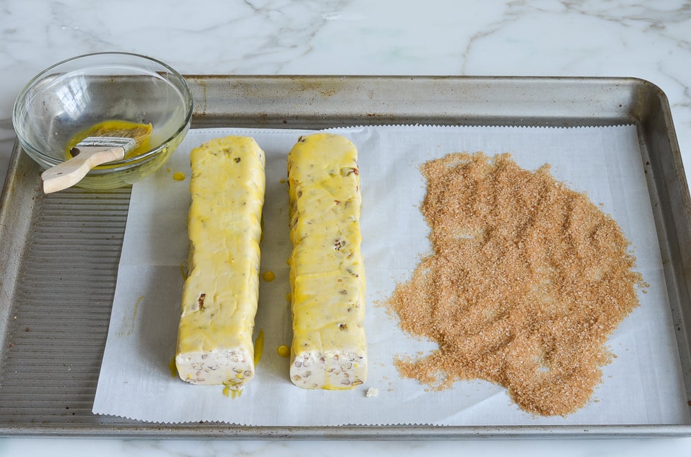 beaten egg yolk, cookie dough logs, and turbinado sugar on counter