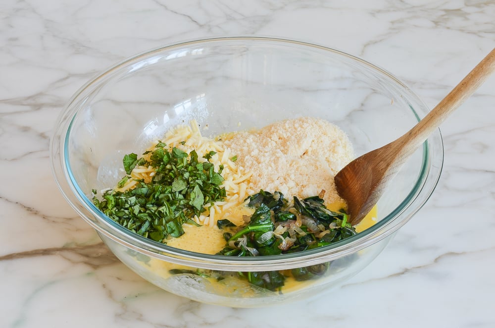 adding spinach mixture, cheeses, and basil to egg mixture