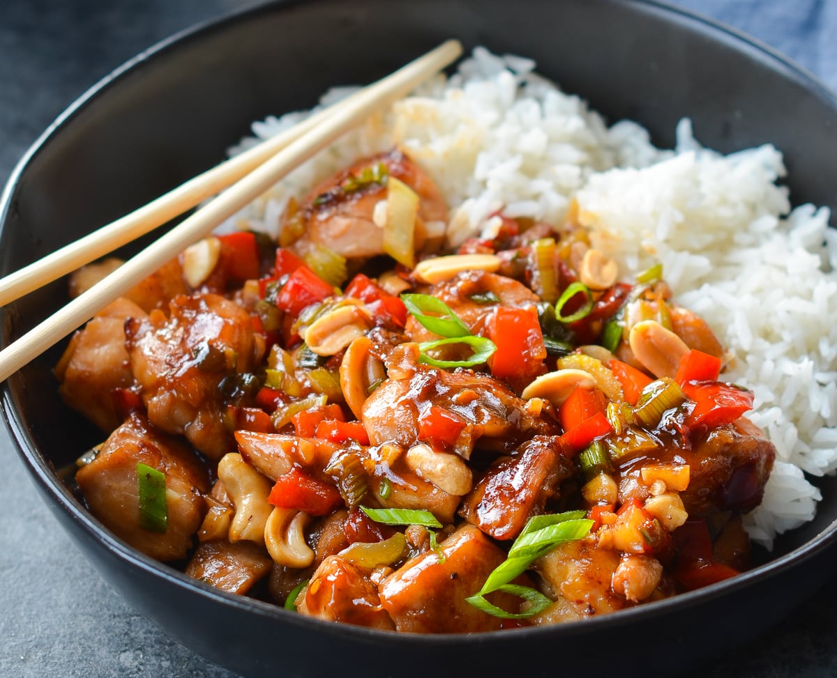 kung pao chicken in bowl with rice and chop sticks.