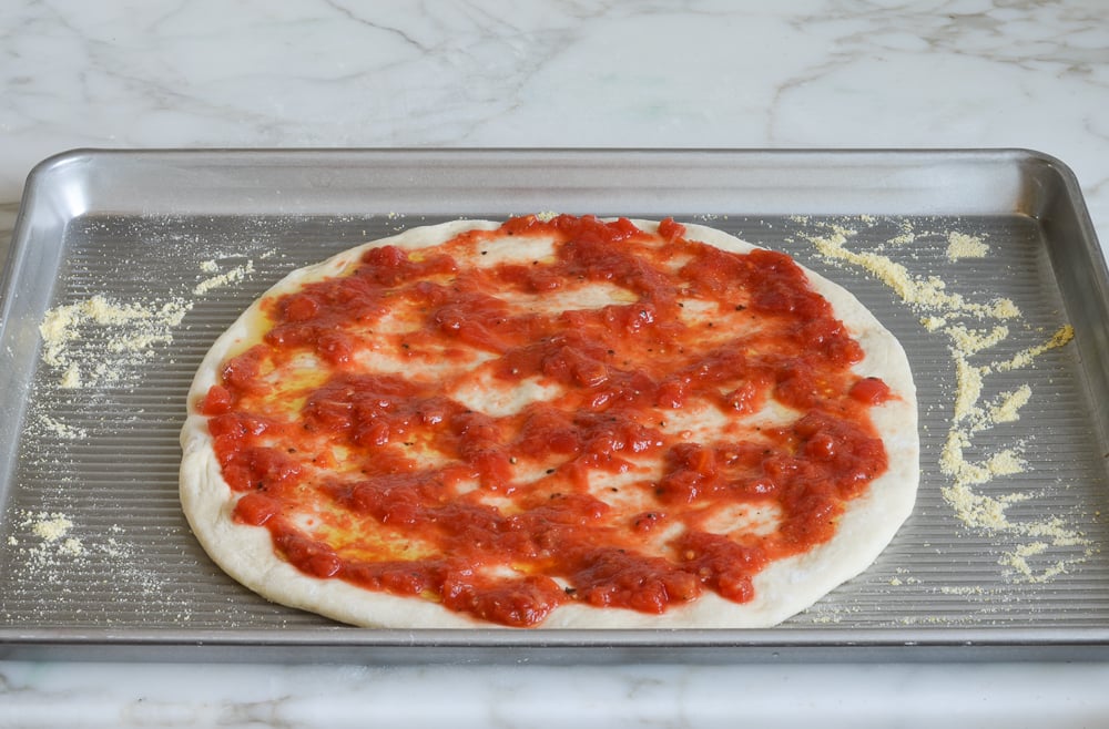 spreading the sauce on the dough