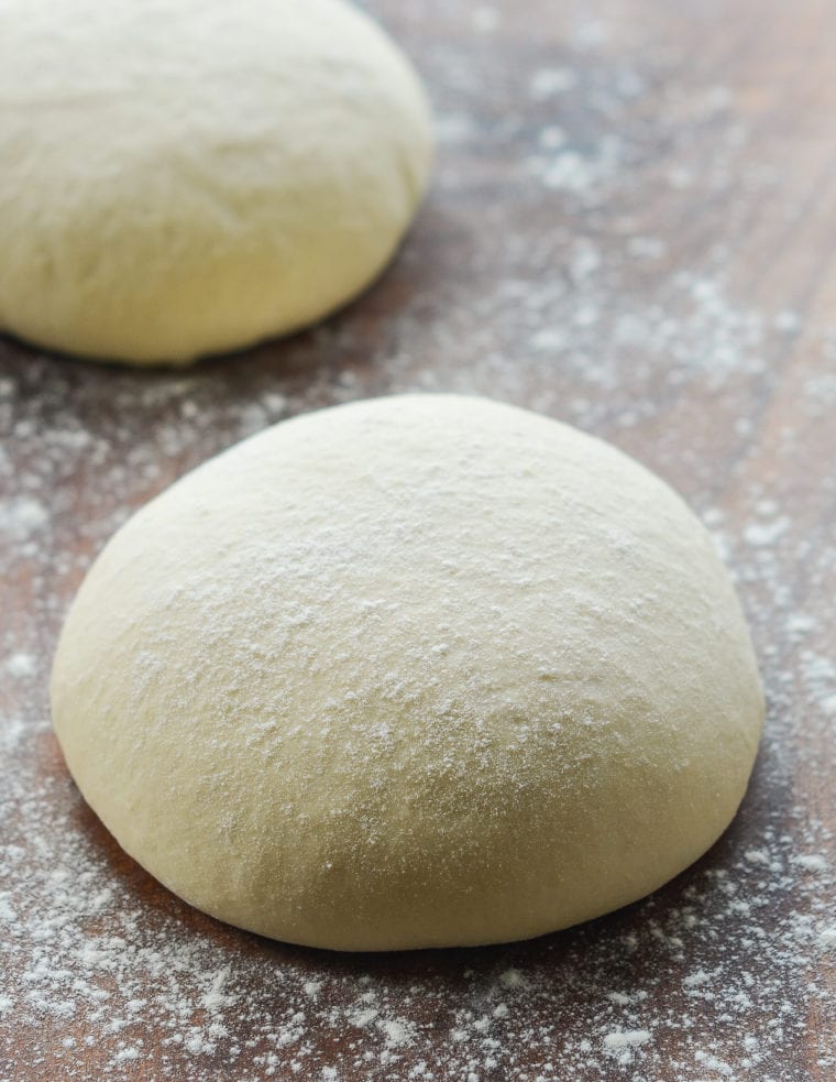 Ball of pizza dough on a floured surface.