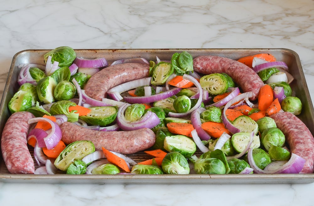 Sausage and vegetables arranged on a sheet pan.