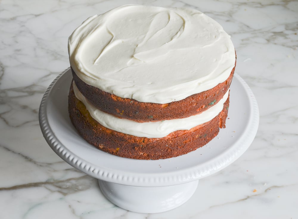 stacking the layers and frosting the sprinkle cake