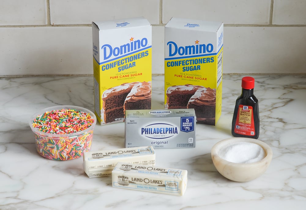 Cake ingredients including cream cheese, sprinkles, and confectioners sugar.