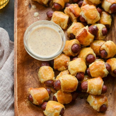 Wooden tray of pigs in a blanket.