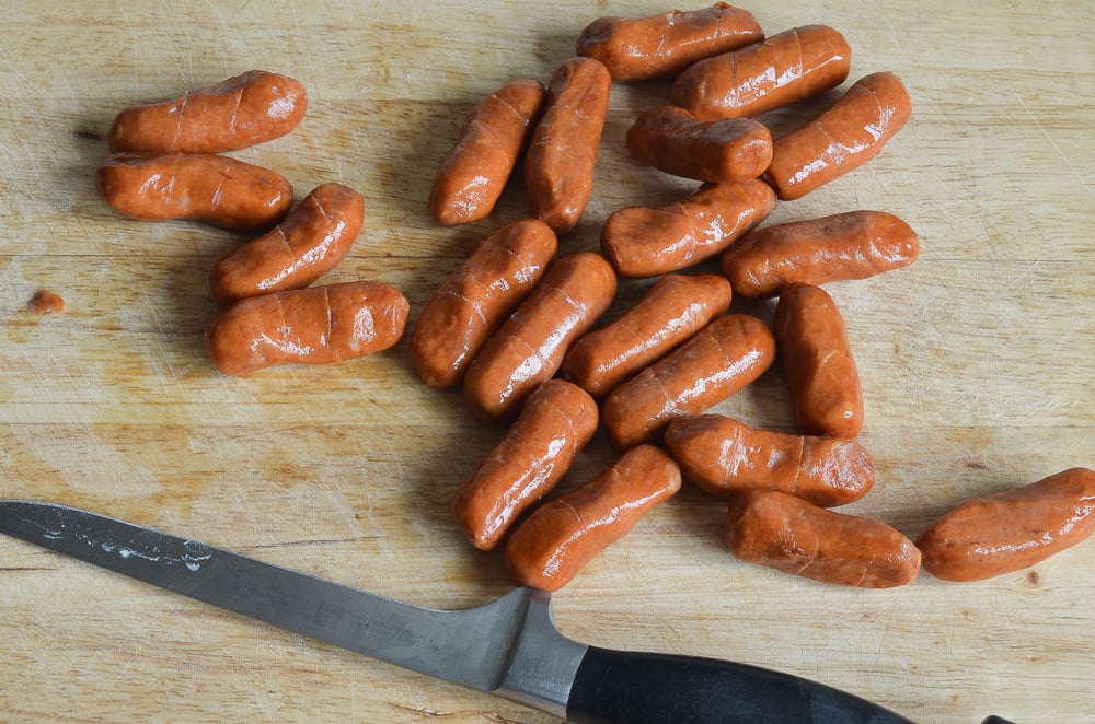 Cocktail sausages on a wooden cutting board.