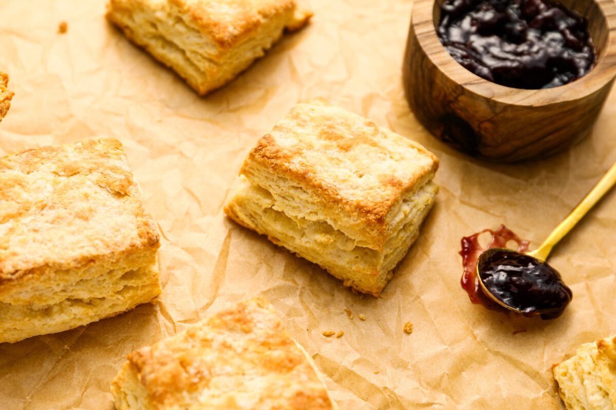 buttermilk biscuits on parchment with spoonful of jelly to the right