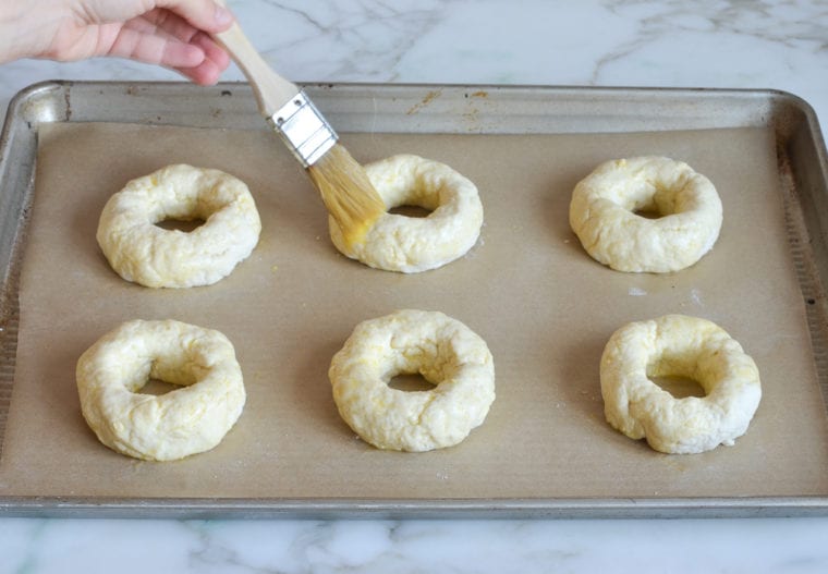 brushing egg wash on bagels