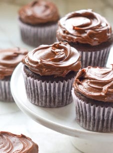 Chocolate cupcakes on an elevated serving dish.