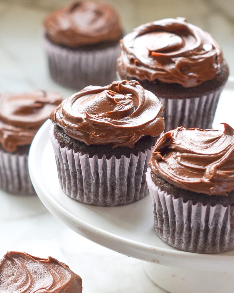 Chocolate cupcakes on an elevated serving dish.