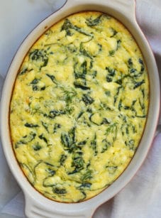 Greek-style spinach, feta, and polenta pie in a baking dish.