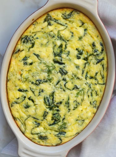 Greek-style spinach, feta, and polenta pie in a baking dish.