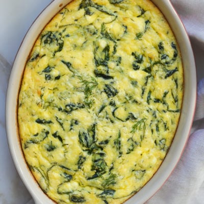 Greek-style spinach, feta, and polenta pie in a baking dish.