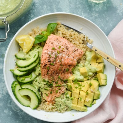 Plate with roasted salmon, quinoa, avocado, cucumber, and green goddess dressing.
