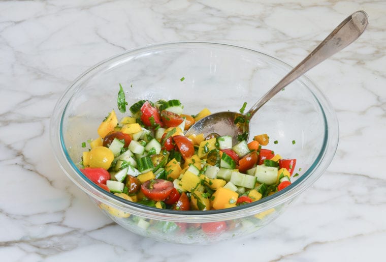 mixing vegetables and herbs with the vinaigrette