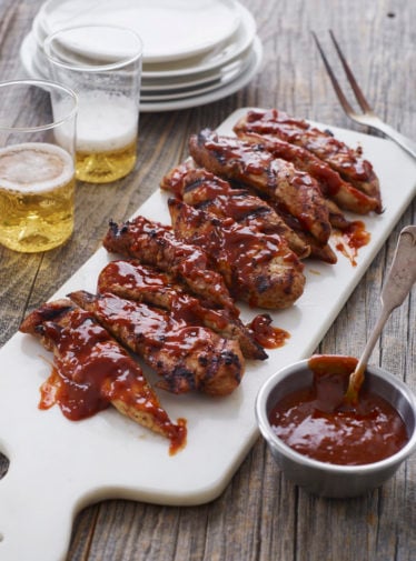 Grilled barbeque chicken on a cutting board.