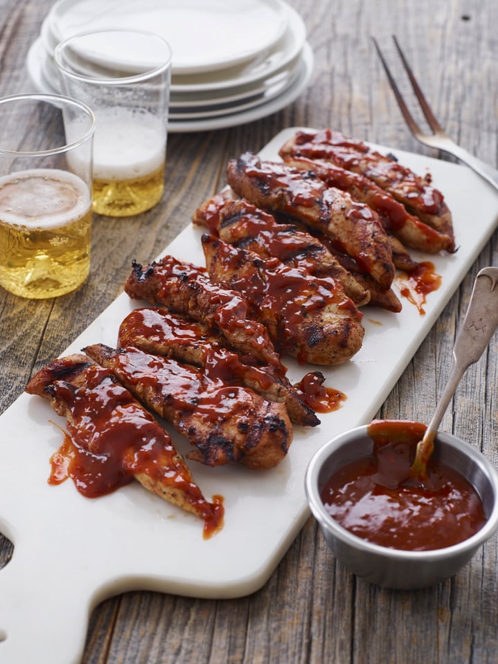Grilled barbeque chicken on a cutting board.