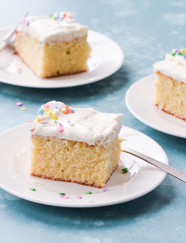 Slices of vanilla sheet cake with cream cheese frosting on plates.