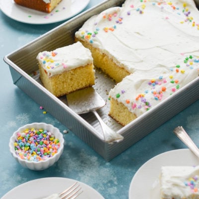 Vanilla sheet cake with cream cheese frosting in a baking dish.