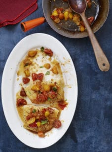 Plate of pan-seared halibut topped with tomatoes.