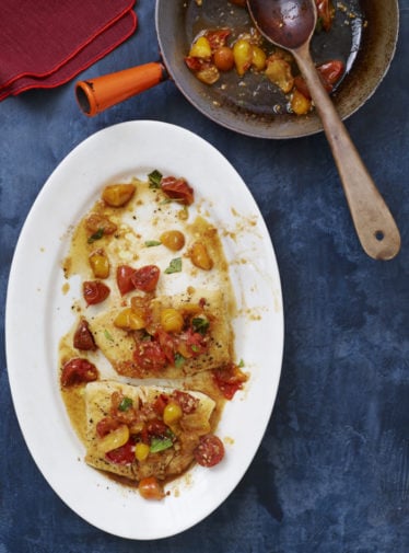 Plate of pan-seared halibut topped with tomatoes.