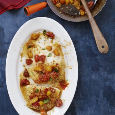 Plate of pan-seared halibut topped with tomatoes.