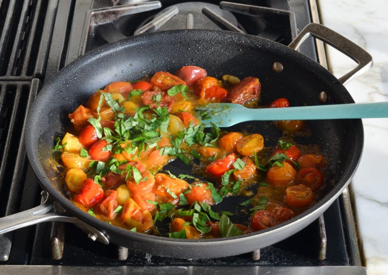 finishing cherry tomato sauce with basil