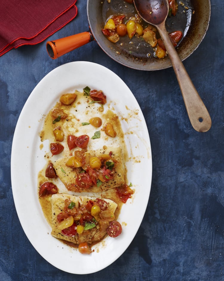 Plate of pan-seared halibut topped with tomatoes.