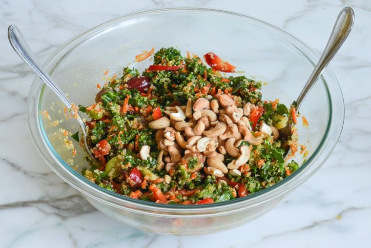 adding cashews to quinoa salad before serving