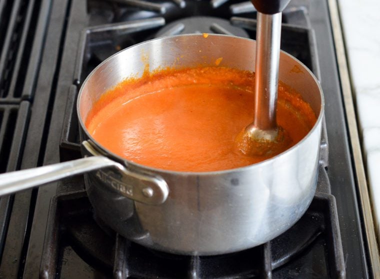 blending the vodka sauce with an immersion blender