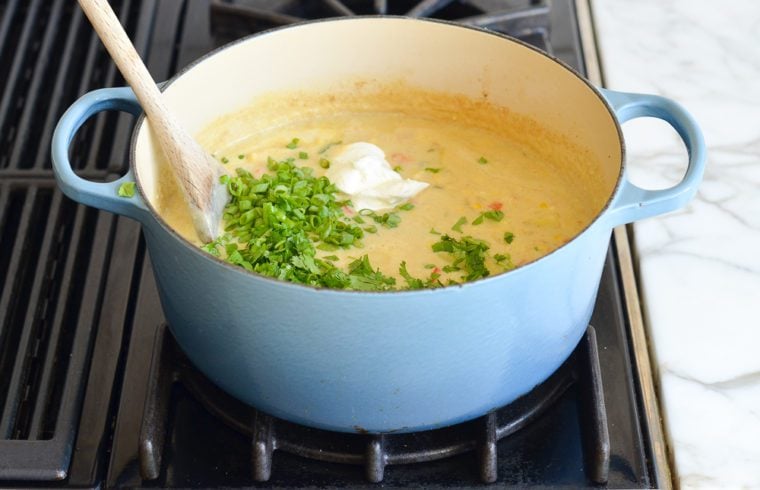 adding scallions, cilantro, and sour cream to corn chowder