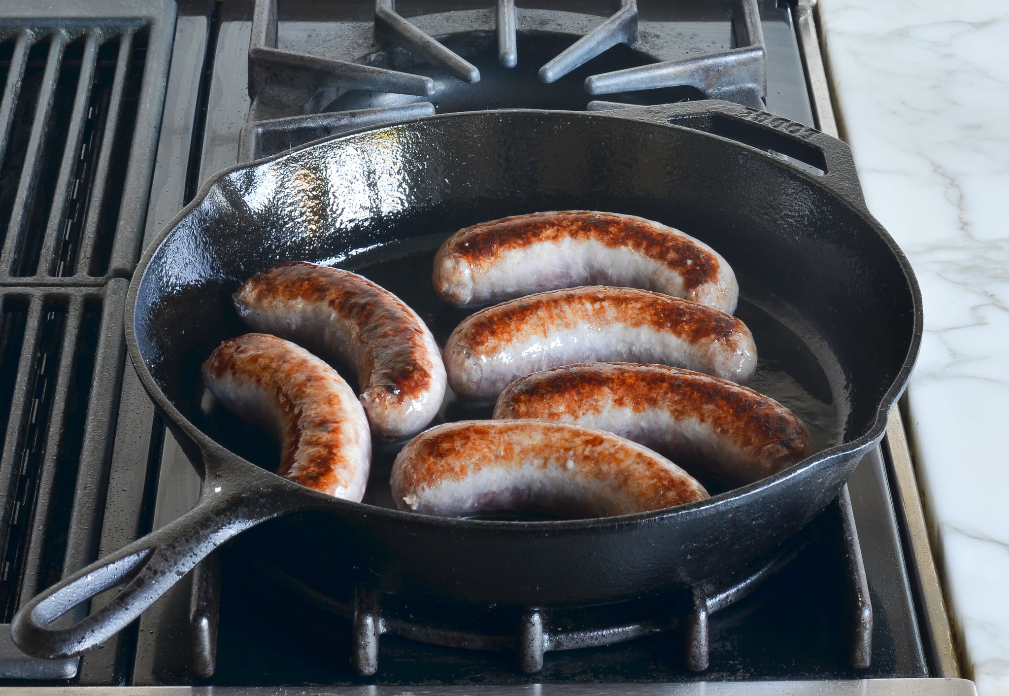 Bratwurst searing in a skillet.