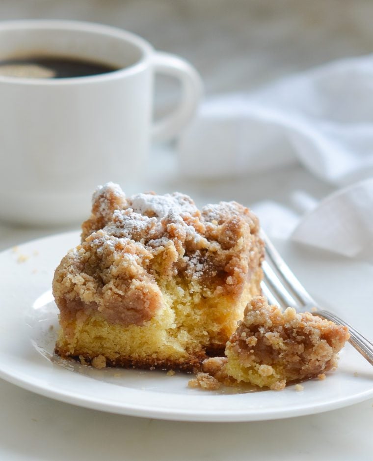 Piece of crumb cake on a plate with a fork.