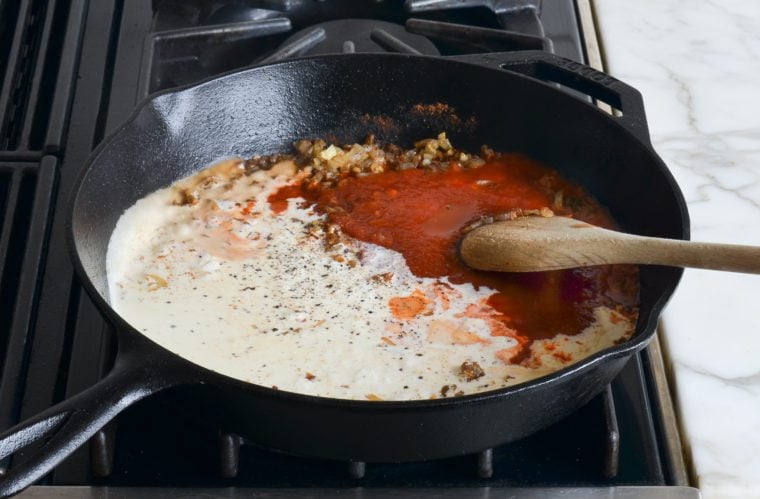 adding cream, tomato sauce, and seasoning