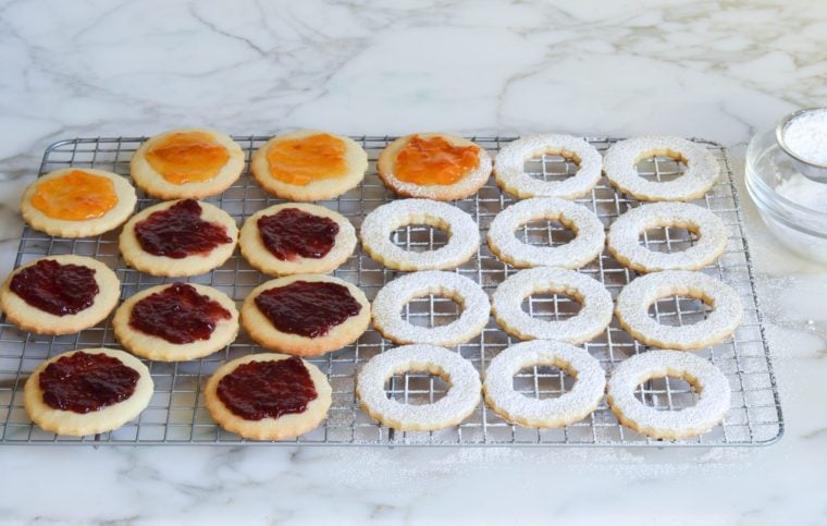 spreading cookies with jam and dusting with Confectioners' sugar