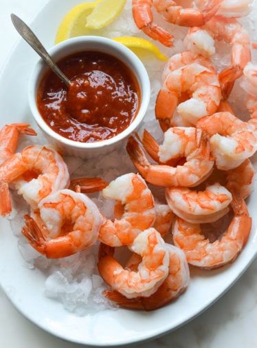 shrimp cocktail and cocktail sauce on a plate over ice.
