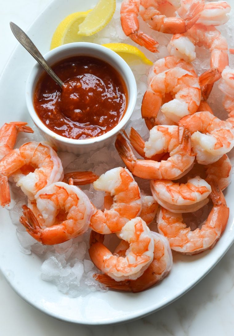 shrimp cocktail and cocktail sauce on a plate over ice.