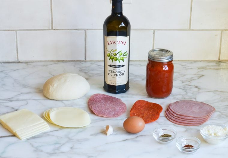 Stromboli ingredients including egg, olive oil, and meats.