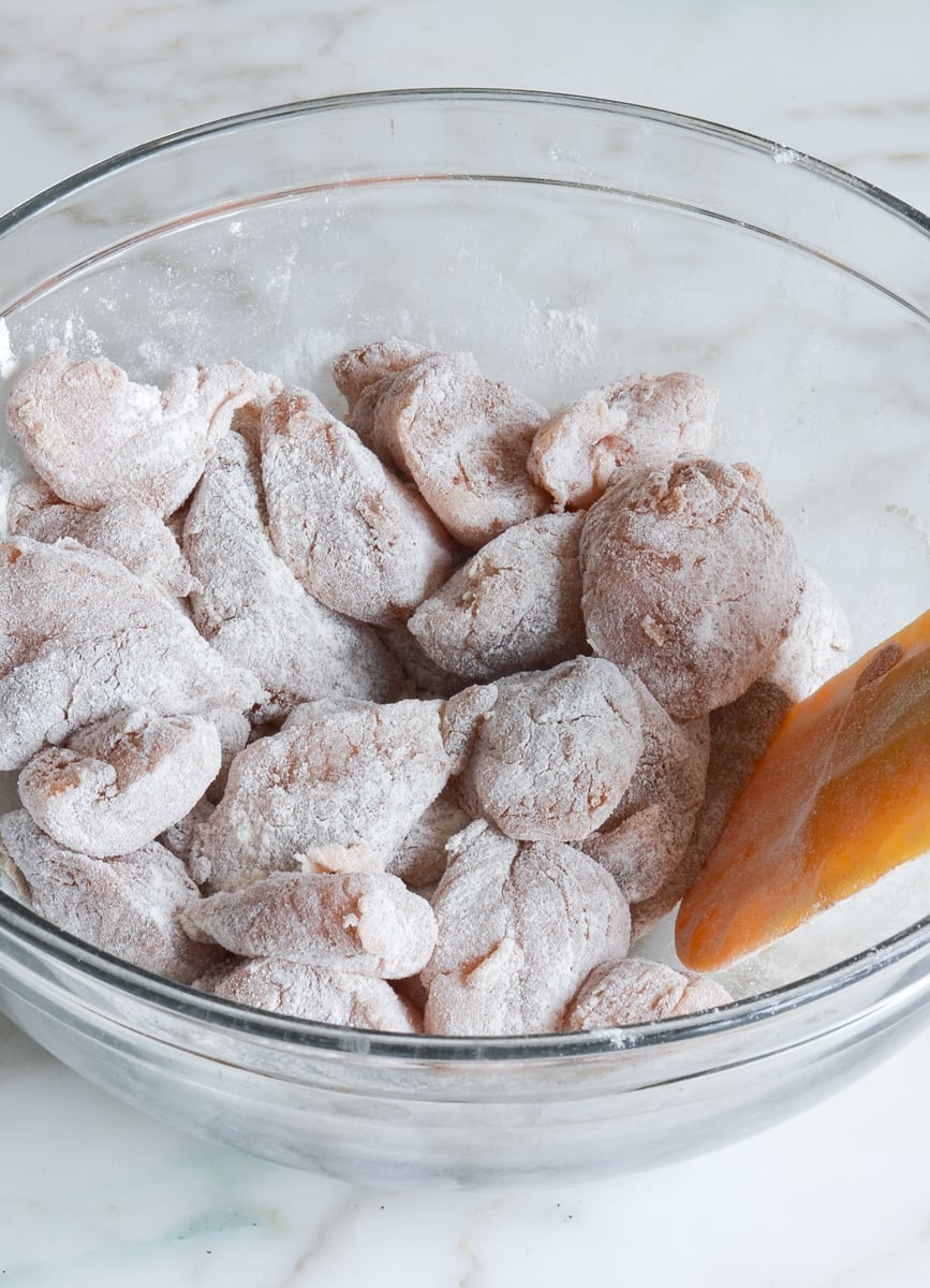 chicken in bowl coated with flour and spice mixture