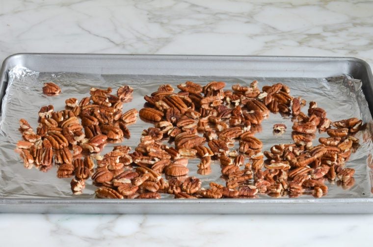 Pecans on a lined baking sheet.