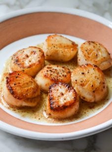 Plate of pan-seared scallops with lemon butter.