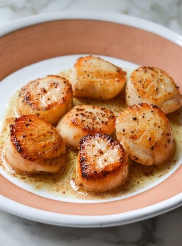 Plate of pan-seared scallops with lemon butter.