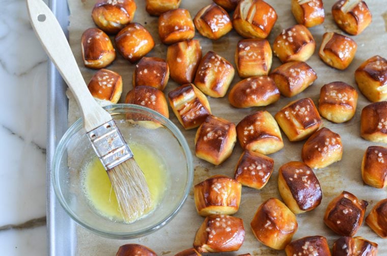brushing melted butter on pretzel bites